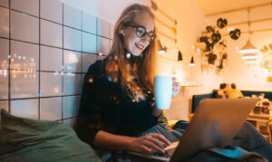 a woman sipping a drink and working on the laptop