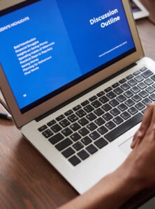 A close-up picture of a laptop with a blurred hand in front