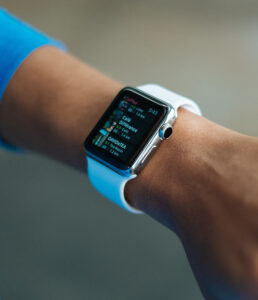 Close-up shot of a person's wrist wearing a silver Apple Watch with a white band